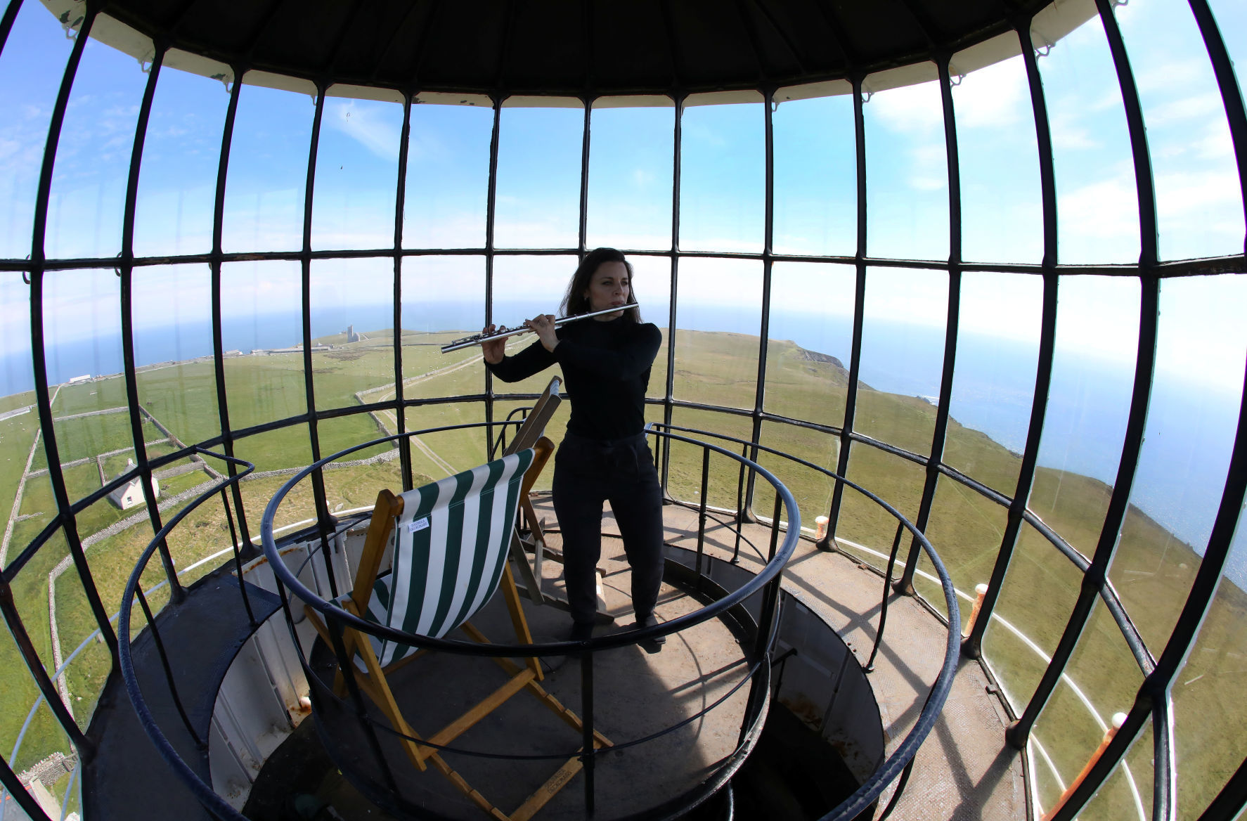 Carolyn Byrne, a lawyer from Manhattan, plays her flute at the top of the 'Old Light' lighthouse during the Cloud Appreciation Society's gathering in Lundy